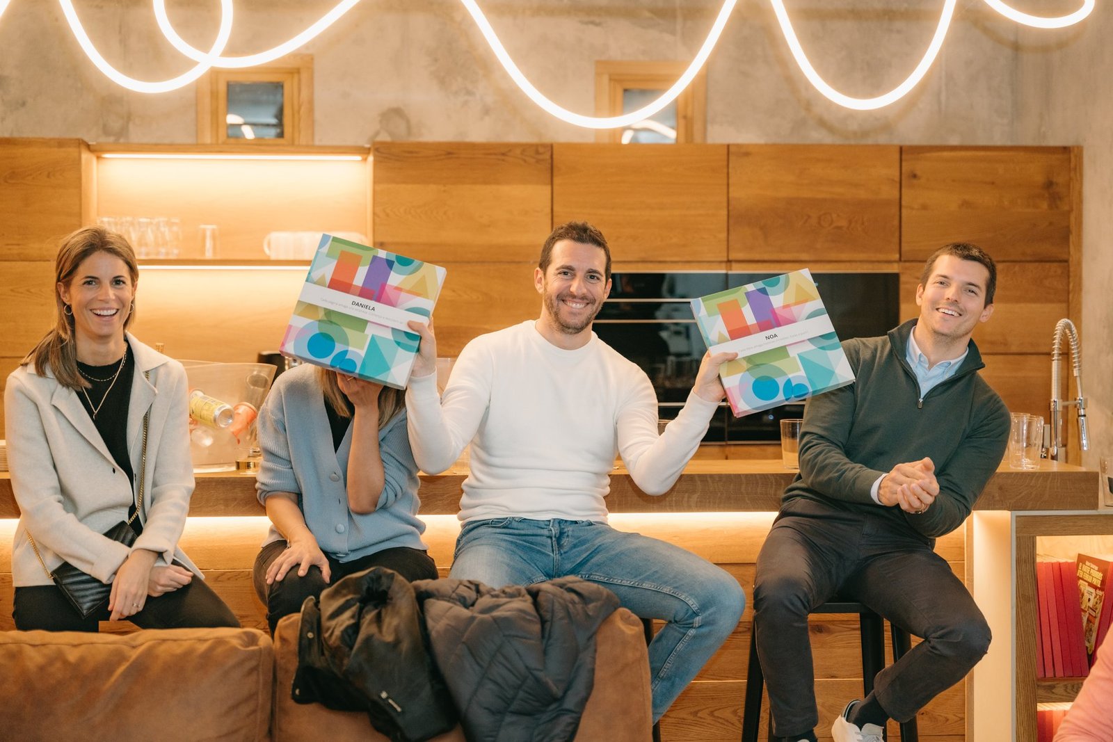 Cuatro personas sonríen en un evento. Dos hombres y una mujer muestran los nuevos productos KALEIDOBOOK personalizados "Daniela" y "Noa".